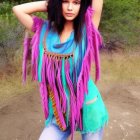 Blue-haired woman in pink and turquoise fringe clothing against desert backdrop