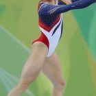 Female gymnast in red, white, blue leotard against green floral backdrop