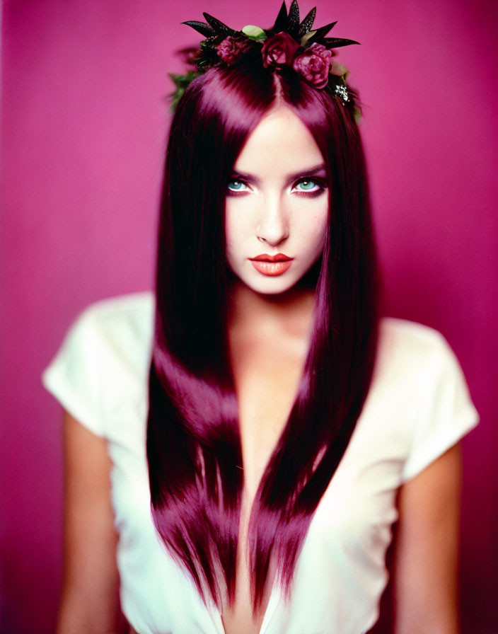 Burgundy-haired woman with blue eyes in white top and floral headpiece