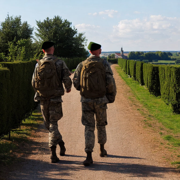 Military soldiers in camouflage uniforms walking on tree-lined pathway.