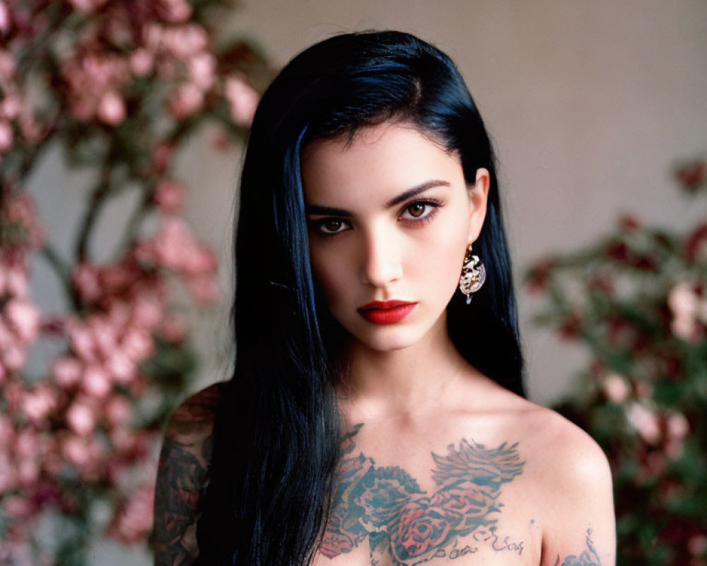 Woman with Black Hair and Tattoos Poses Among Pink Blossoms