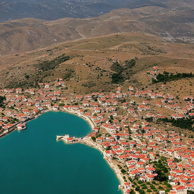 Coastal Town with Red-Roofed Buildings in Bay and Rolling Hills