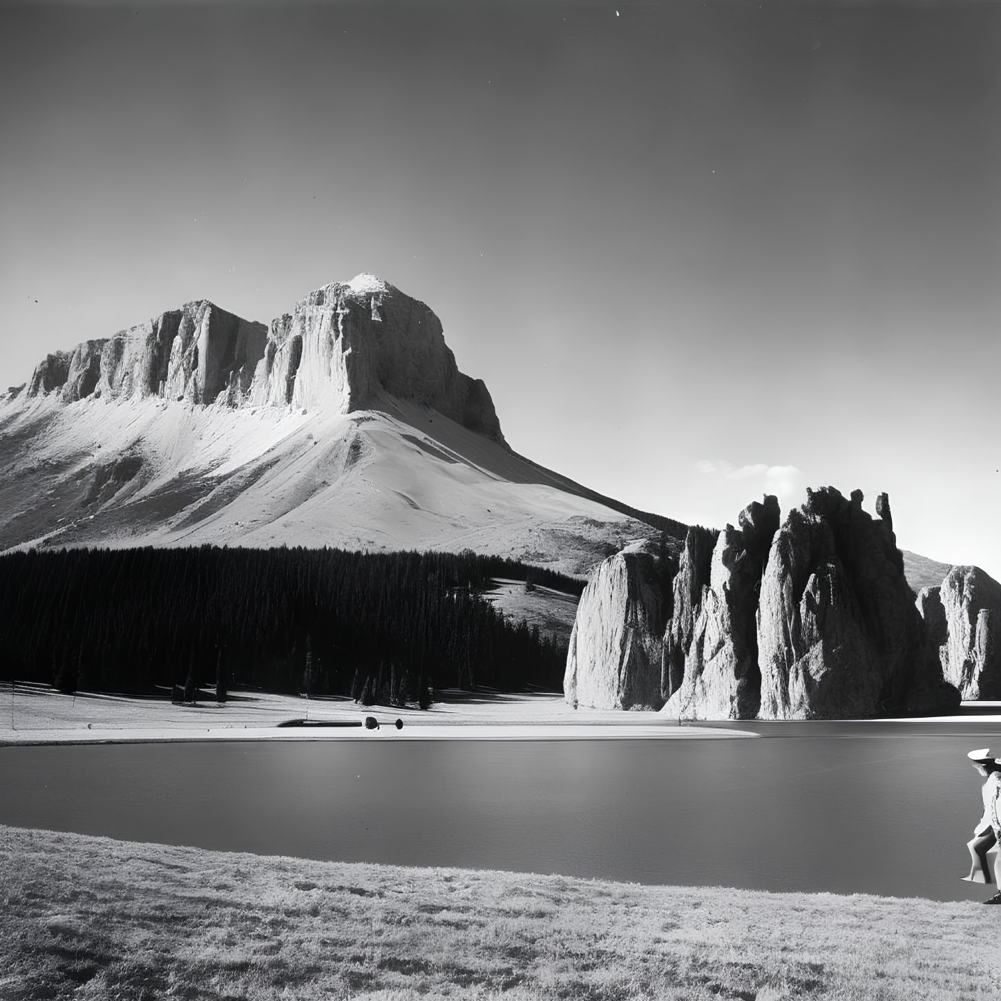 Monochrome landscape with mountain, lake, and person in wide-brimmed hat