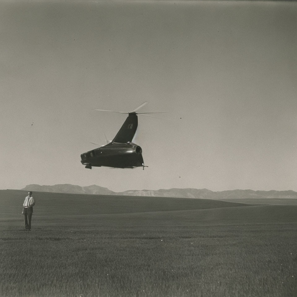 Monochrome image of person in field watching helicopter above mountains