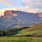 Mystical landscape with sunlit mountains, river, greenery, ancient temple, mist, and