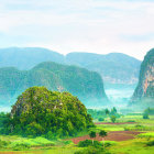 Tranquil landscape with greenery, waterfalls, river, and misty mountains