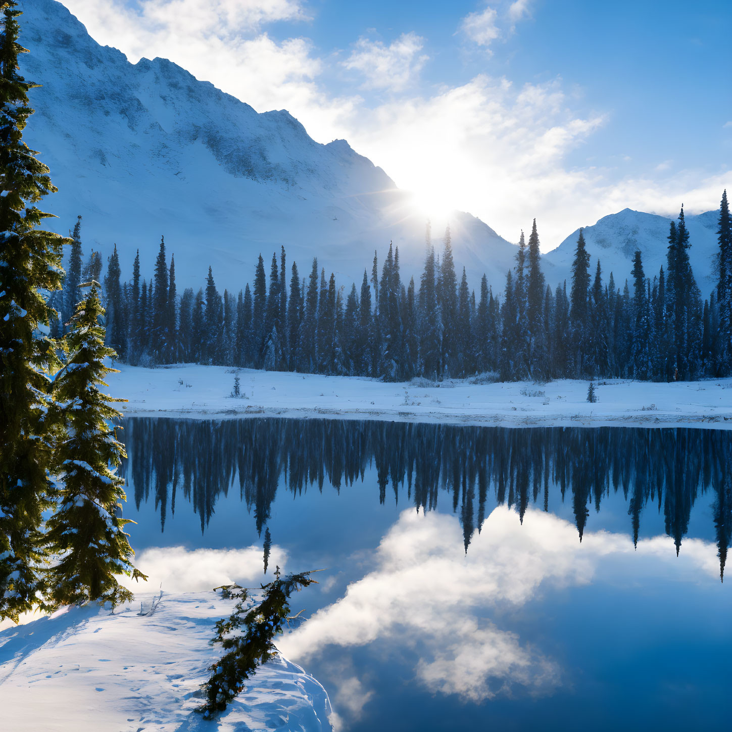 Tranquil snow-covered mountain range at sunrise with forest and lake reflection