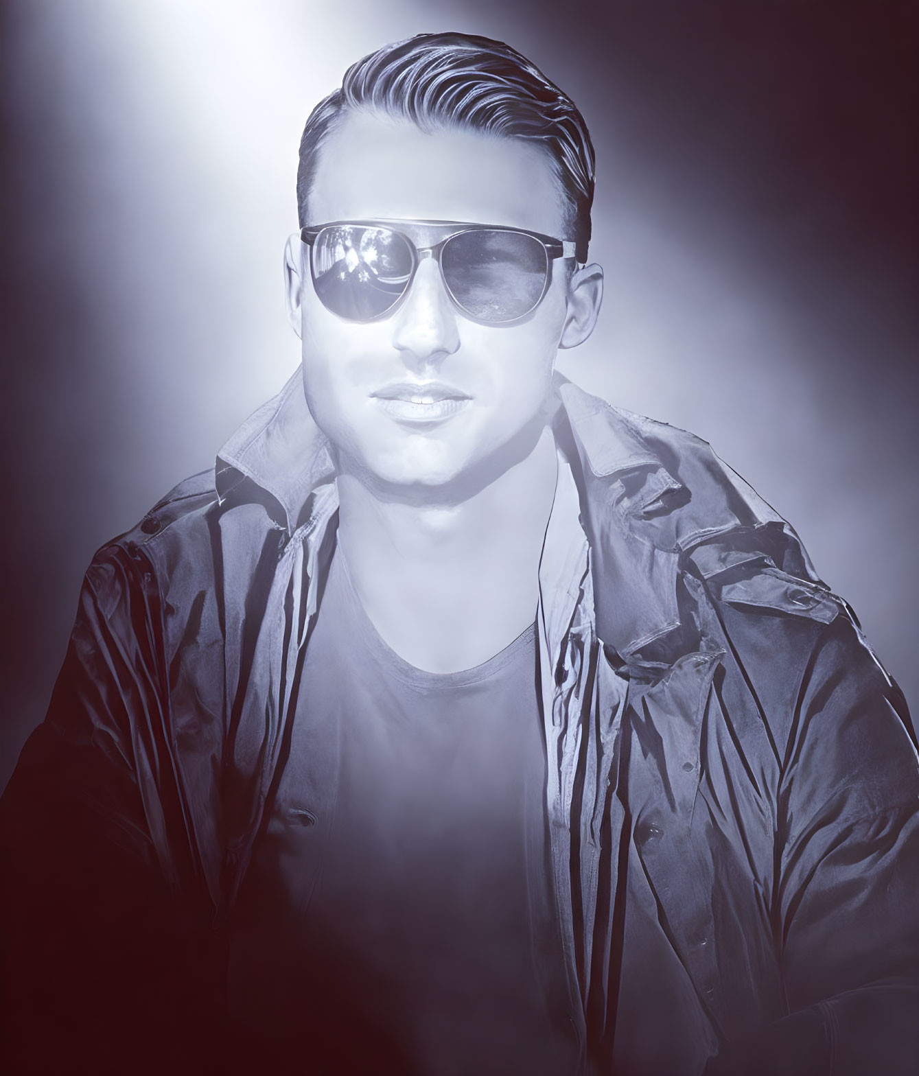 Monochrome image of a man in sunglasses with slicked-back hair and jacket under hazy light.