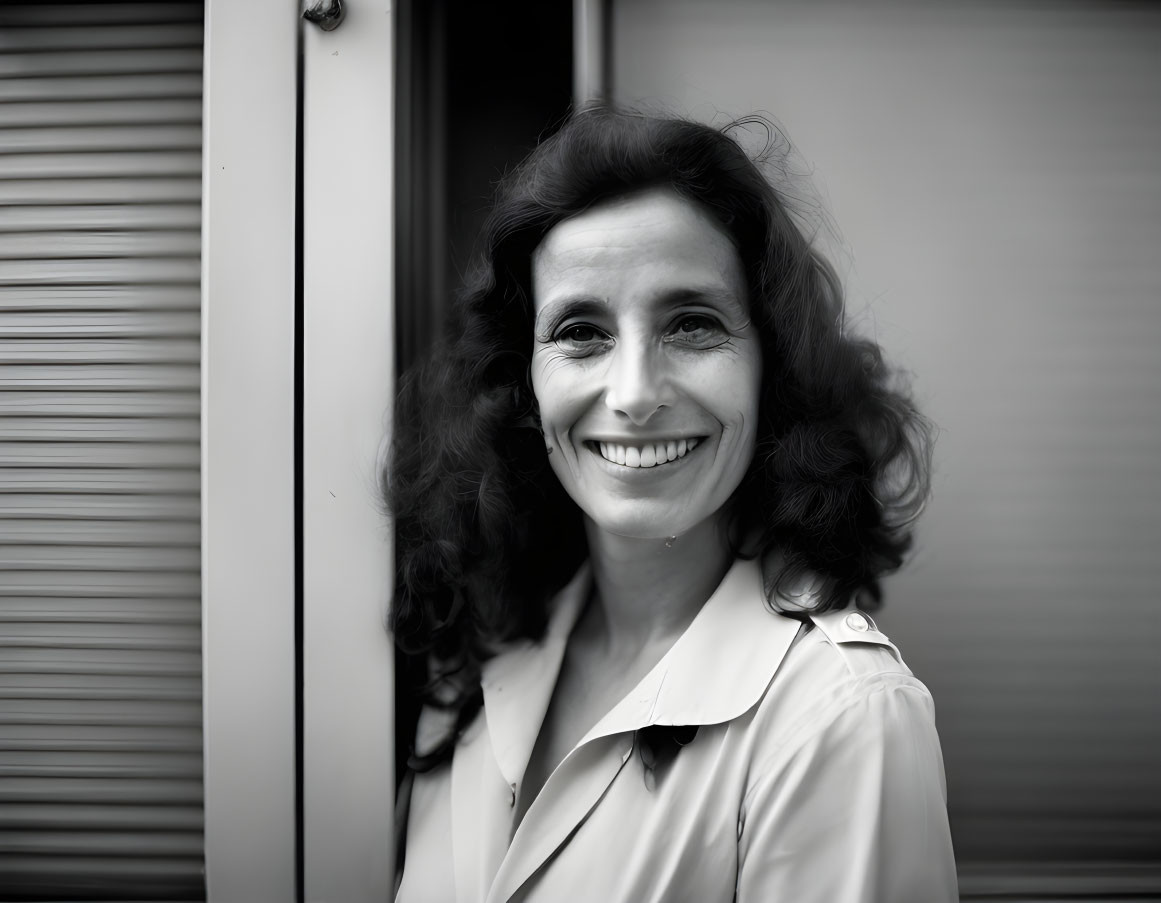 Monochrome portrait: Smiling woman with curly hair by a door