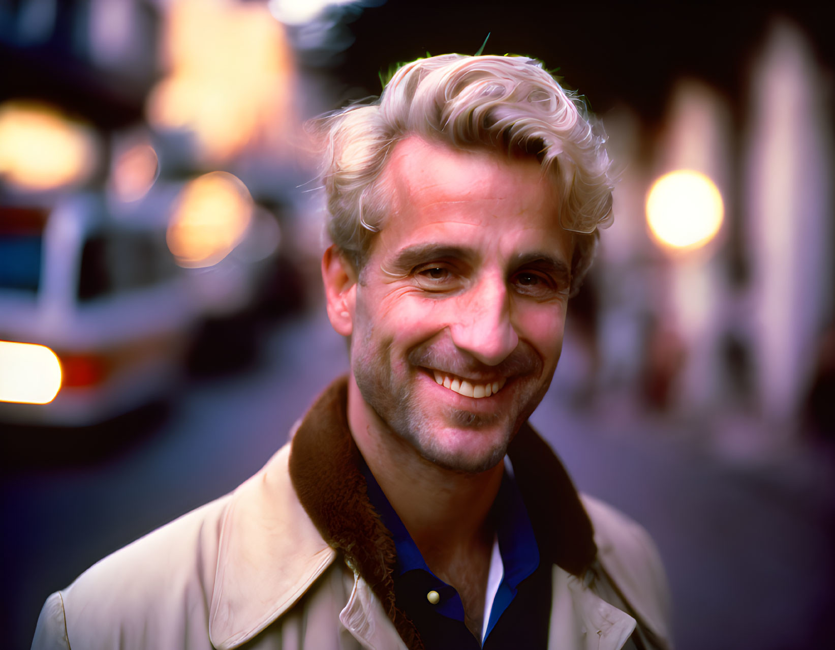 Blond man in beige jacket with fur collar on street background