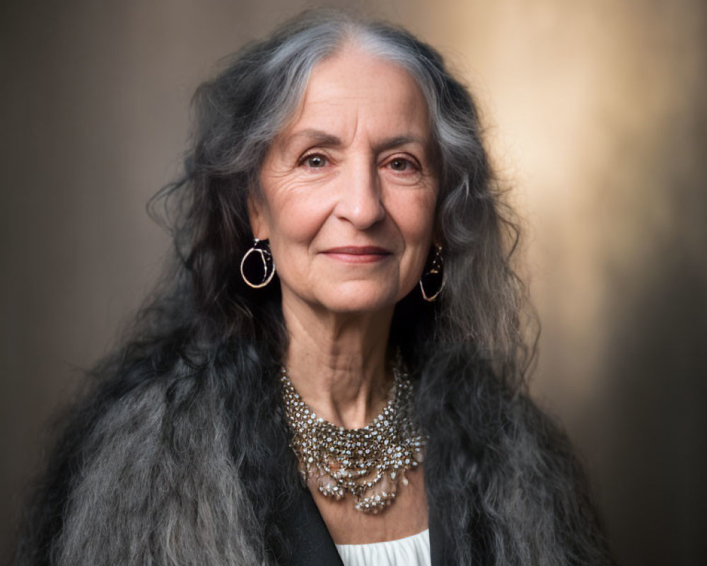 Elderly woman with gray hair and earrings smiling in white blouse and necklace