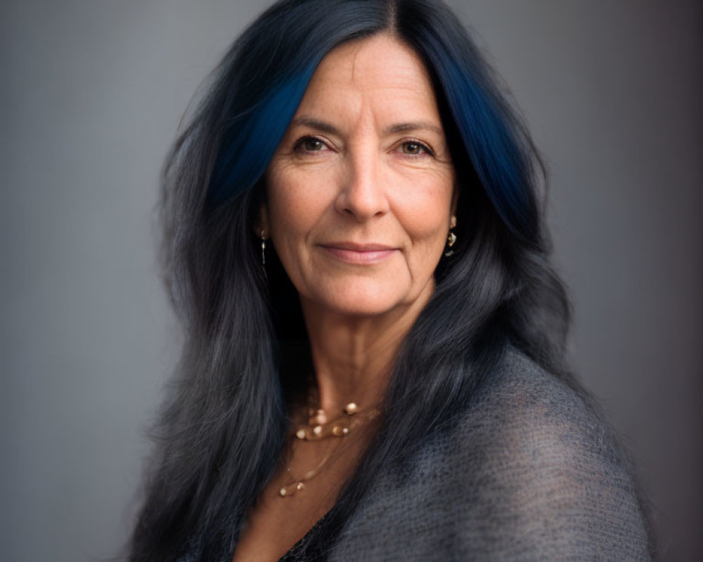 Mature woman with blue-streaked gray hair in gray top portrait