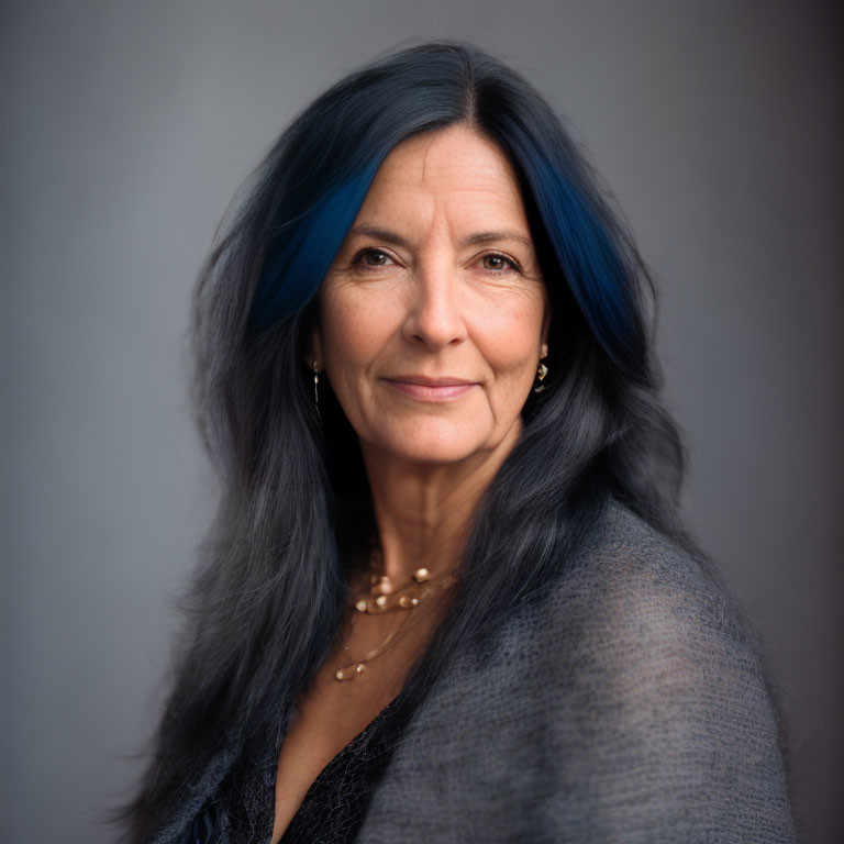 Mature woman with blue-streaked gray hair in gray top portrait