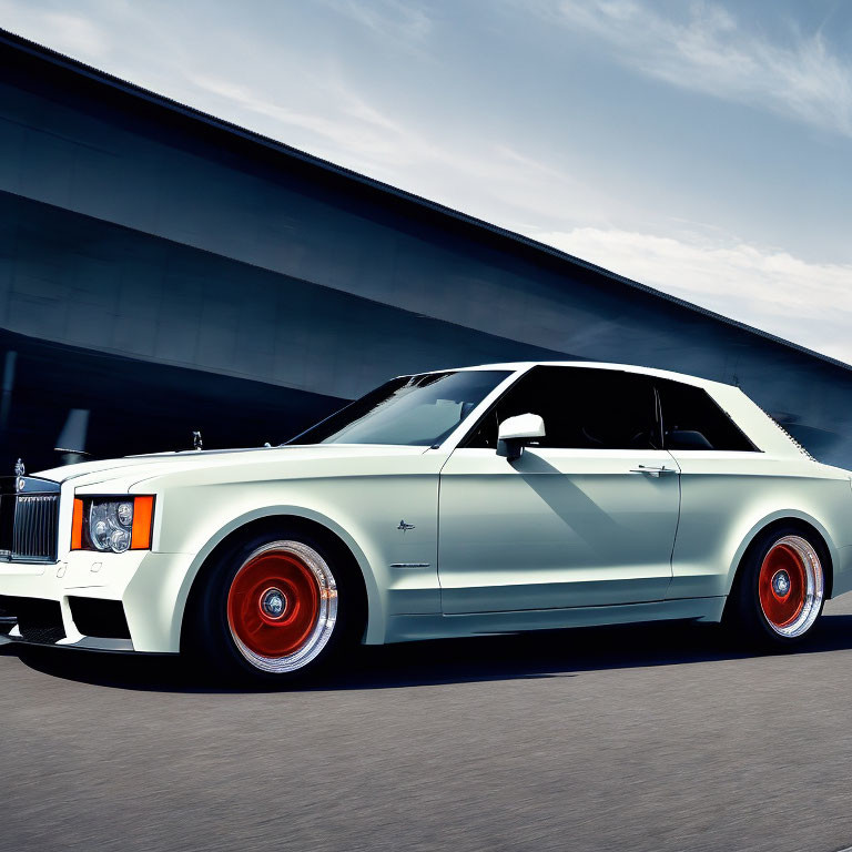 Luxury White Coupe with Black Roof & Red Wheels in Motion