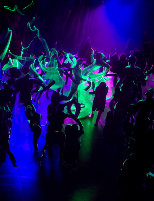 Neon green streaks illuminate dancers in dimly lit club