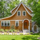 Charming wooden cottage with white trim and porch in lush garden