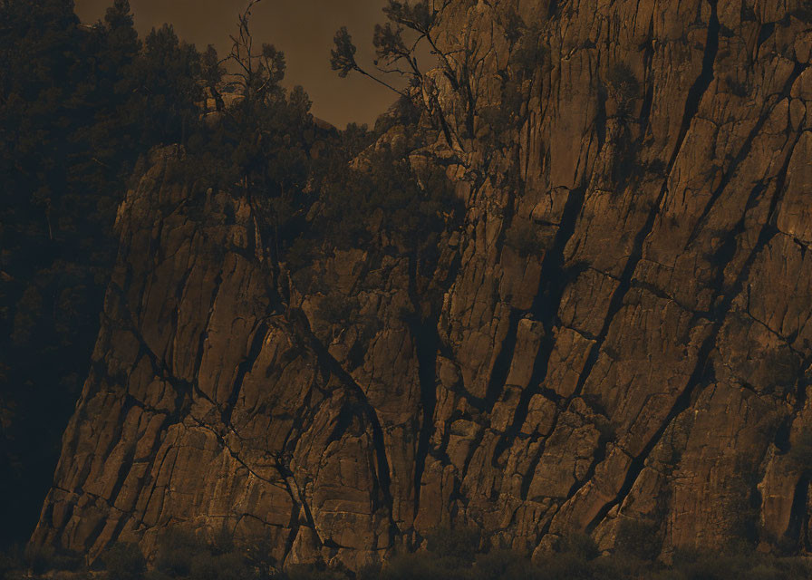 Sepia-toned image of rugged rocky cliff with vertical crevices