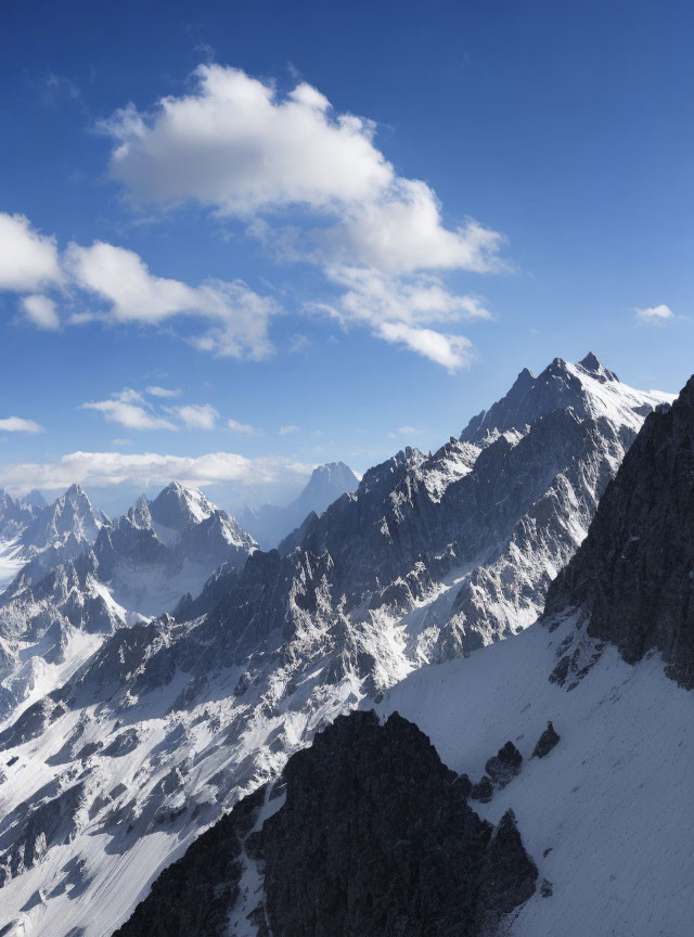 Scenic snow-covered mountain peaks under blue sky with scattered clouds