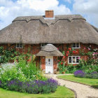 Thatched Roof Cottage Surrounded by Gardens and Cobblestone Path