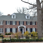 Victorian-style house at twilight with lit windows, blossoming trees, and manicured lawn