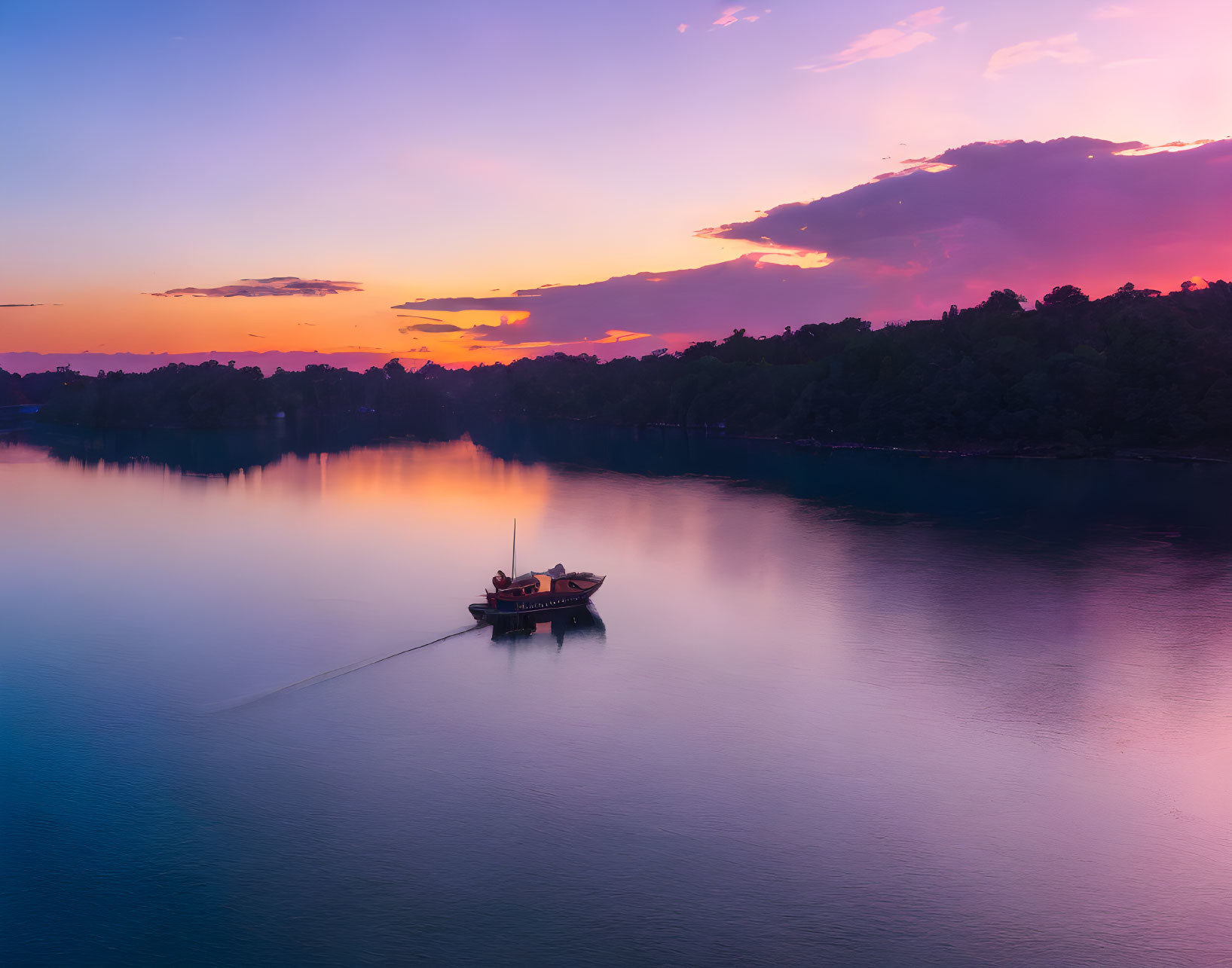 Tranquil sunset scene at lake with boat, trees, and colorful sky