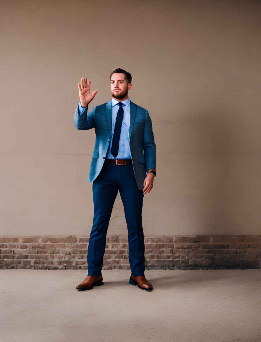 Man in Blue Suit and Tie Raising Right Hand against Neutral Background