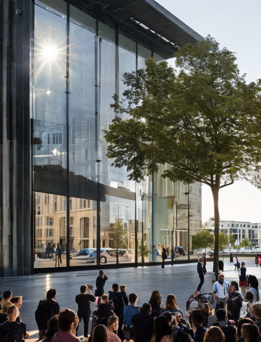 People outside modern glass building in urban plaza.