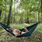 Dog relaxing on star-patterned hammock in lush forest with triangular structure