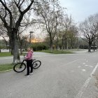 Fantastical figure with glowing orb head in serene park with blooming white trees