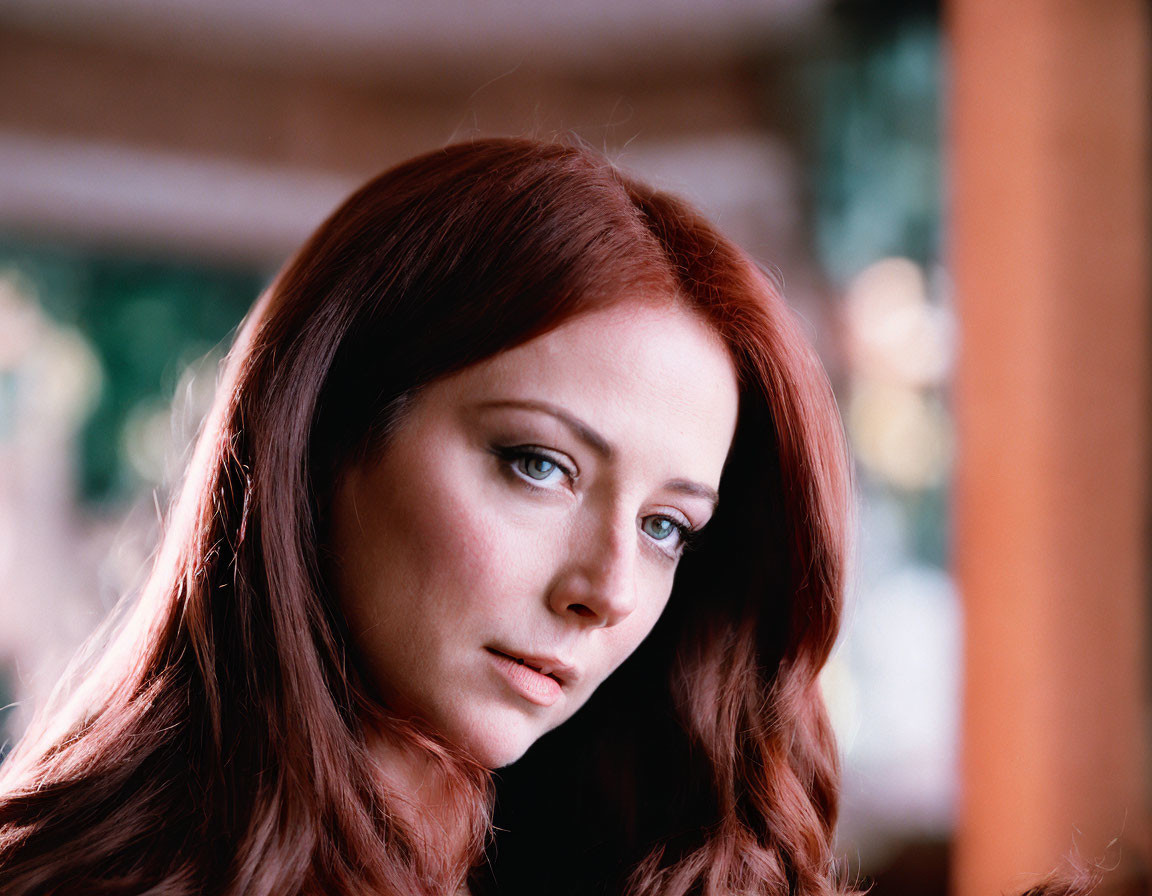 Long red-haired woman with reflective expression indoors.