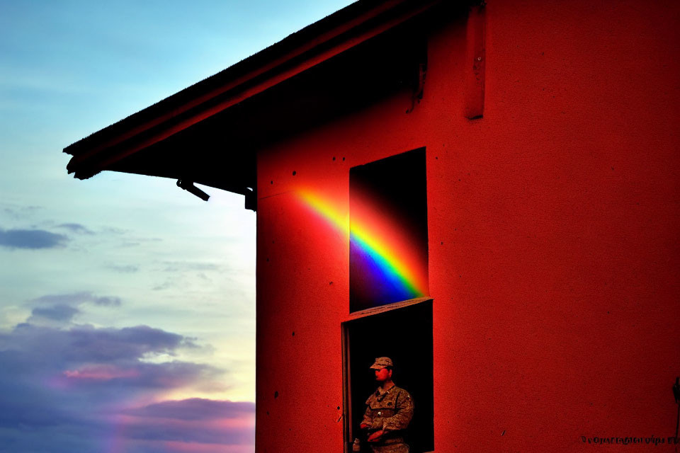 Camouflaged soldier beside building with colorful light spectrum at sunset