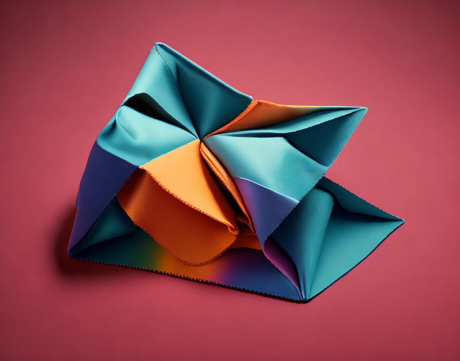 Vibrant origami structure with blue, orange, and teal sections on pink backdrop