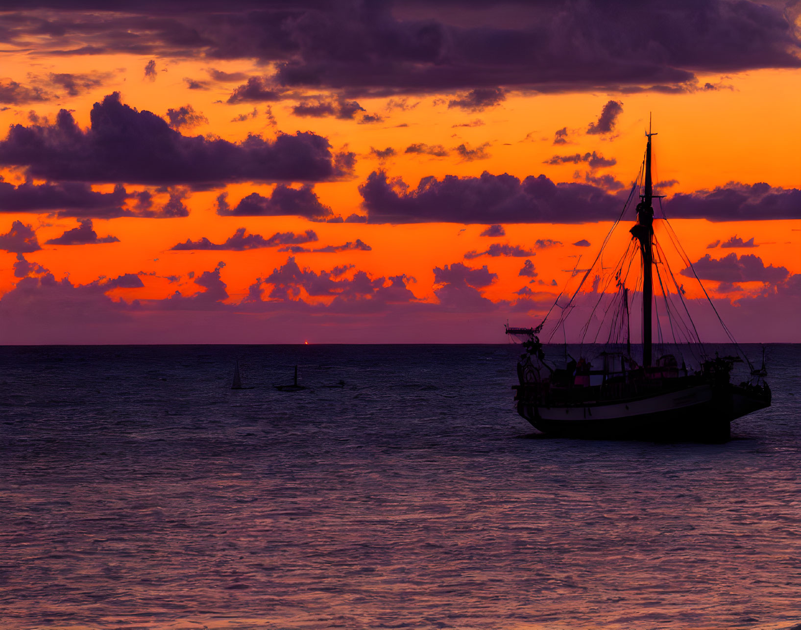 Sailboat silhouette on vibrant orange and purple sunset sky