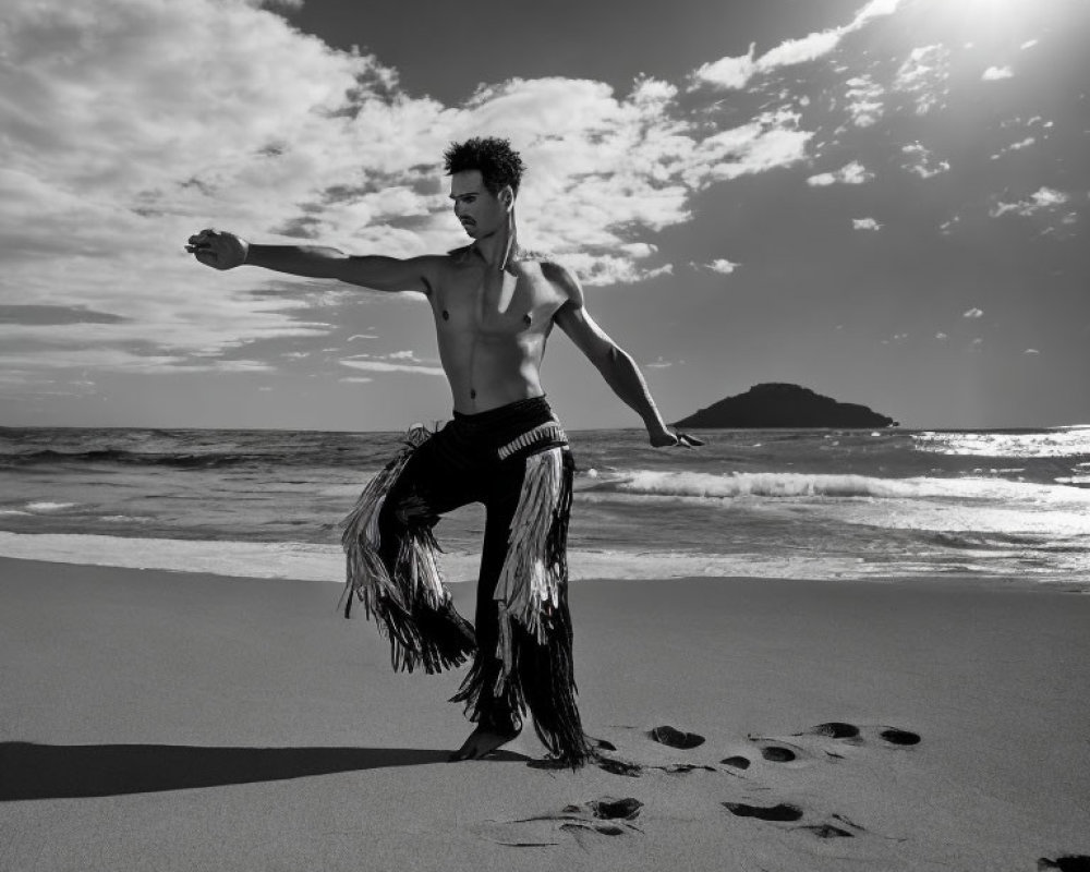 Male dancer in fringed pants poses on beach at sunset