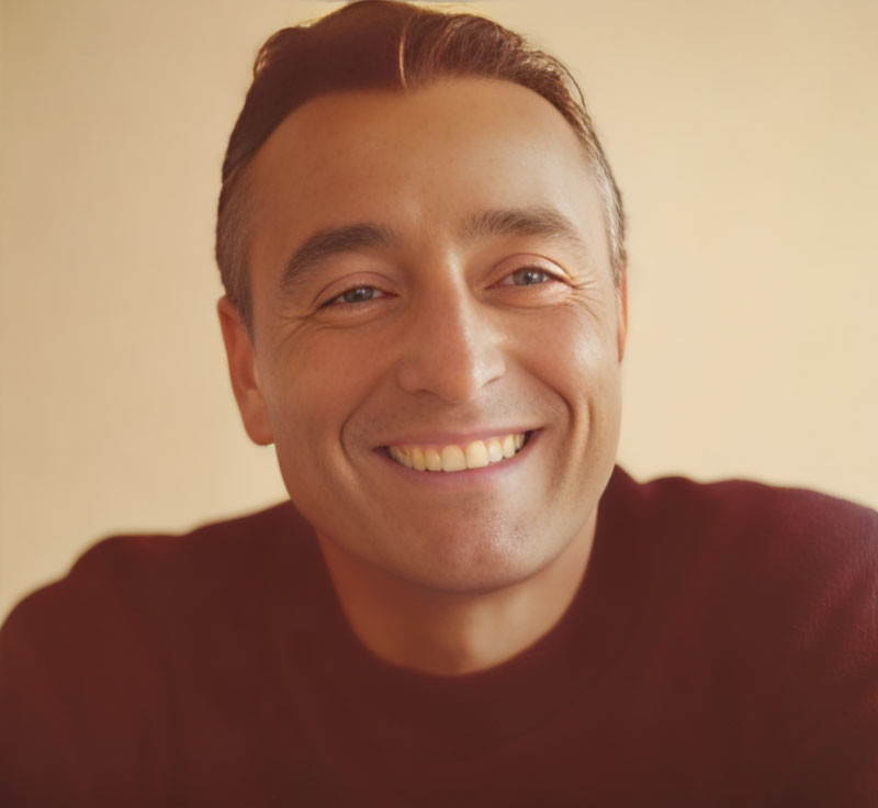 Smiling man with short hair in burgundy shirt on beige background