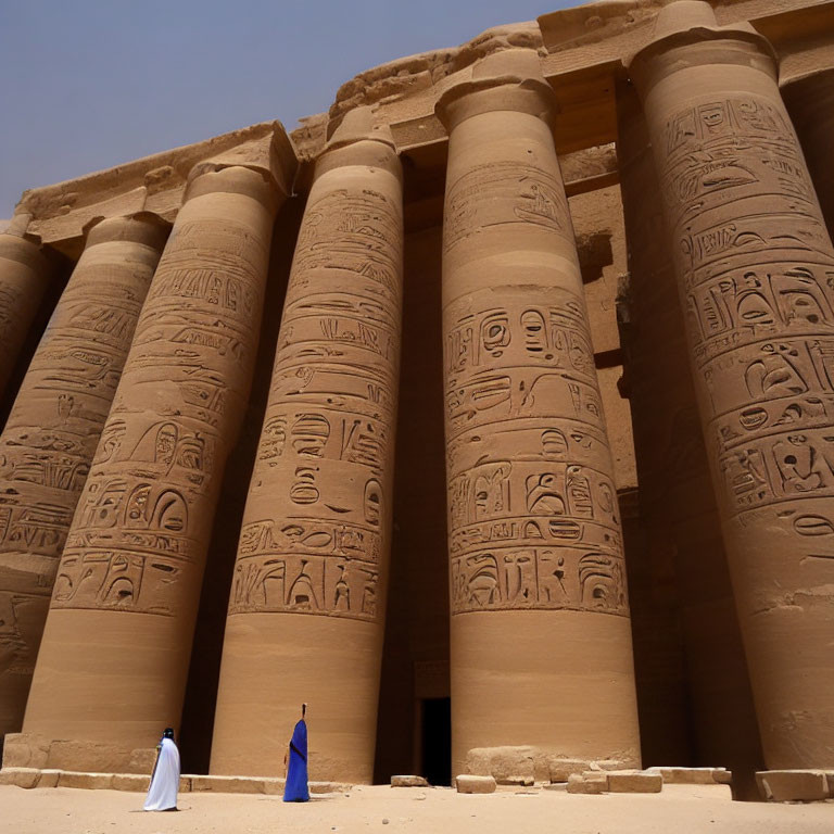 Traditional robed individuals at ancient Egyptian temple columns