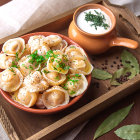 Savory dumplings with herbs, sour cream, corn, and peas on wooden table