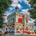 Ornate red building with blue domes in lush green landscape