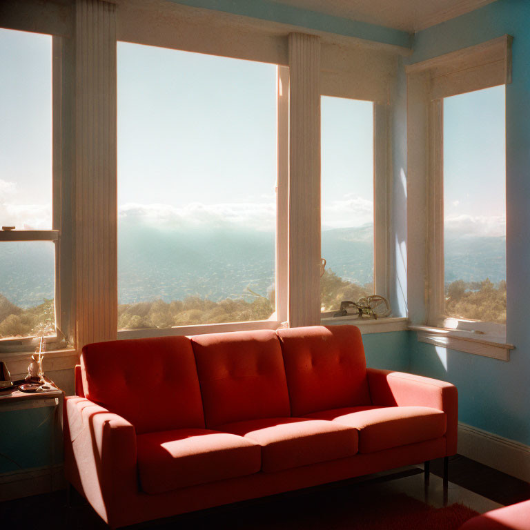 Room with Large Window and Scenic Landscape View Featuring Bright Red Sofa