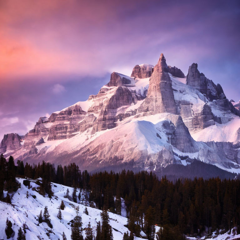 Snow-capped mountain peaks at sunrise with purple and orange sky