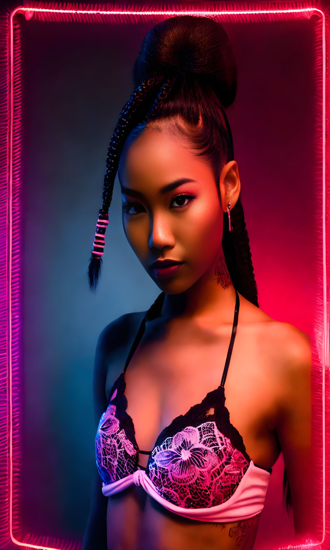 Elaborate updo and braids on woman in lace bra under neon lights