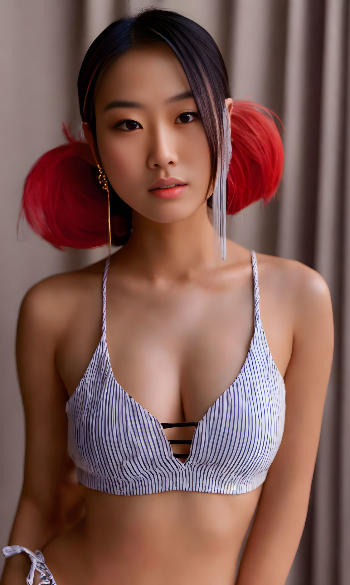 Red-tipped pigtails woman in striped bikini against curtain.