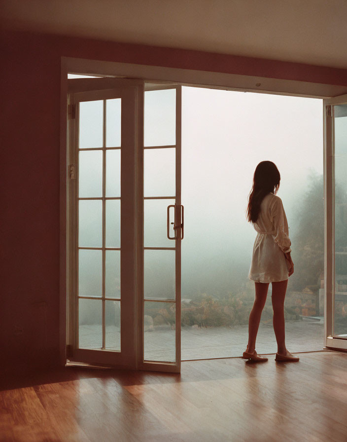 Woman Standing by Open Door Gazing at Misty Waterfront View