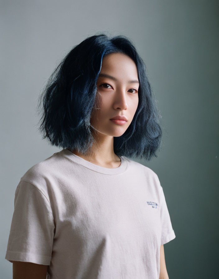 Woman with Blue-Tinted Hair in Beige T-Shirt on Gray Background