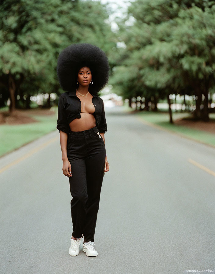 Confident woman with afro hairstyle on tree-lined road