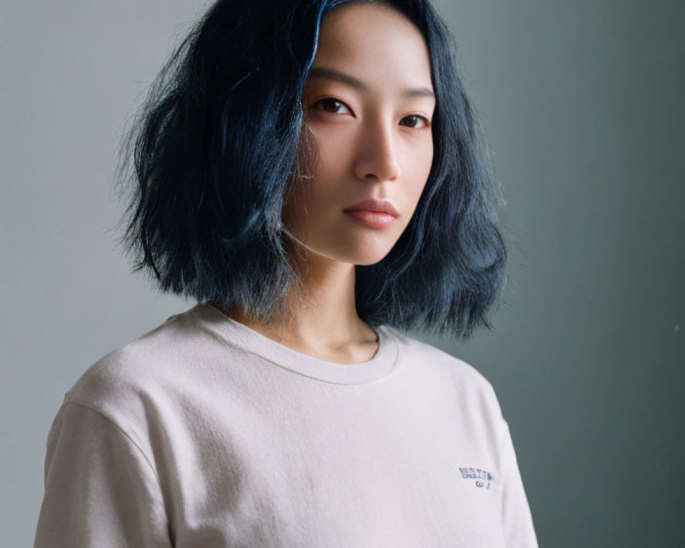 Woman with Blue-Tinted Hair in Beige T-Shirt on Gray Background