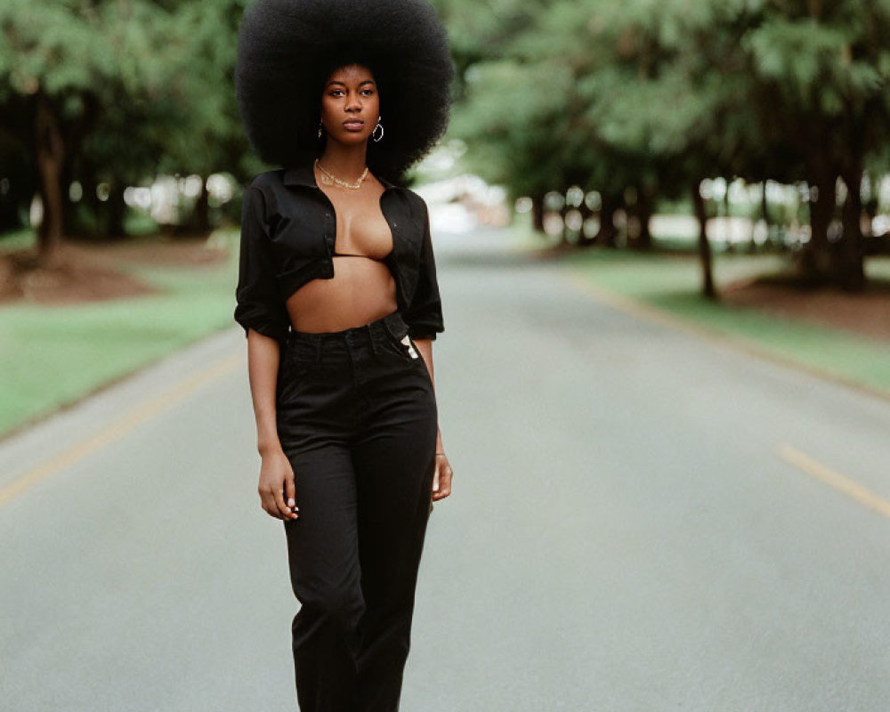 Confident woman with afro hairstyle on tree-lined road