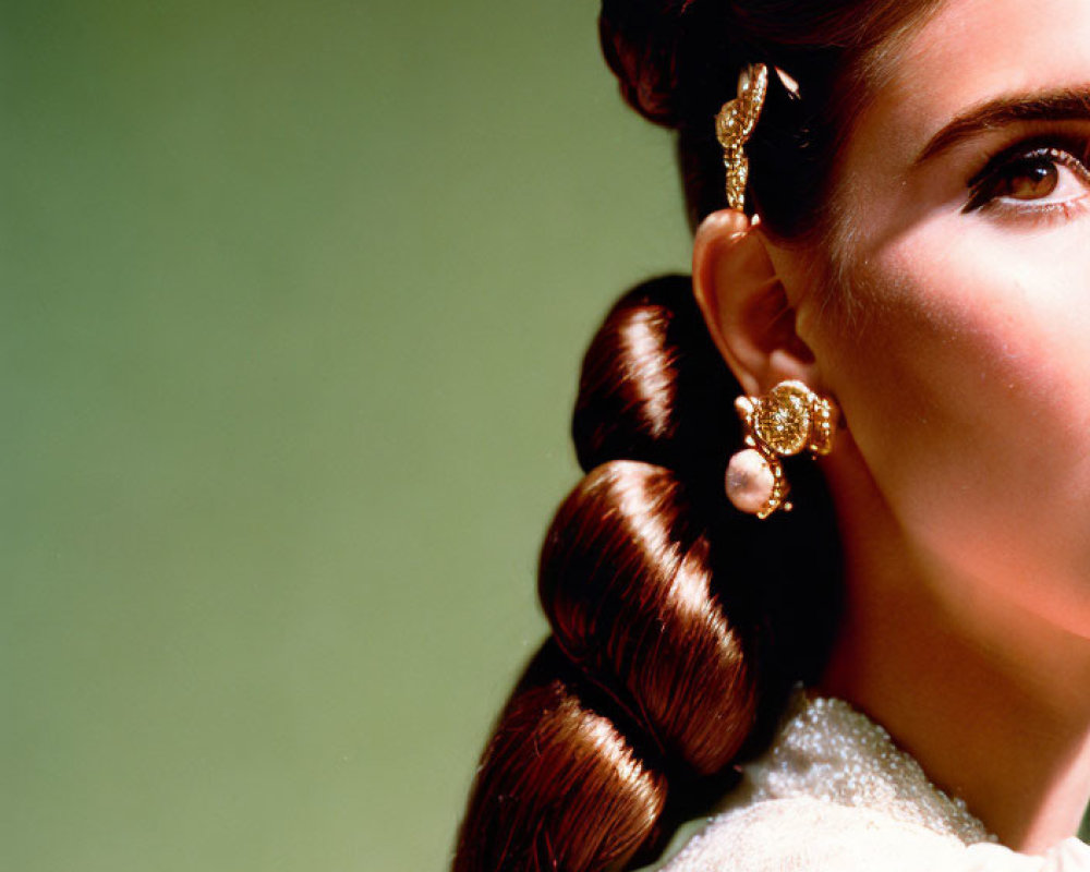 Portrait of person with styled hair braid and earring on soft green background