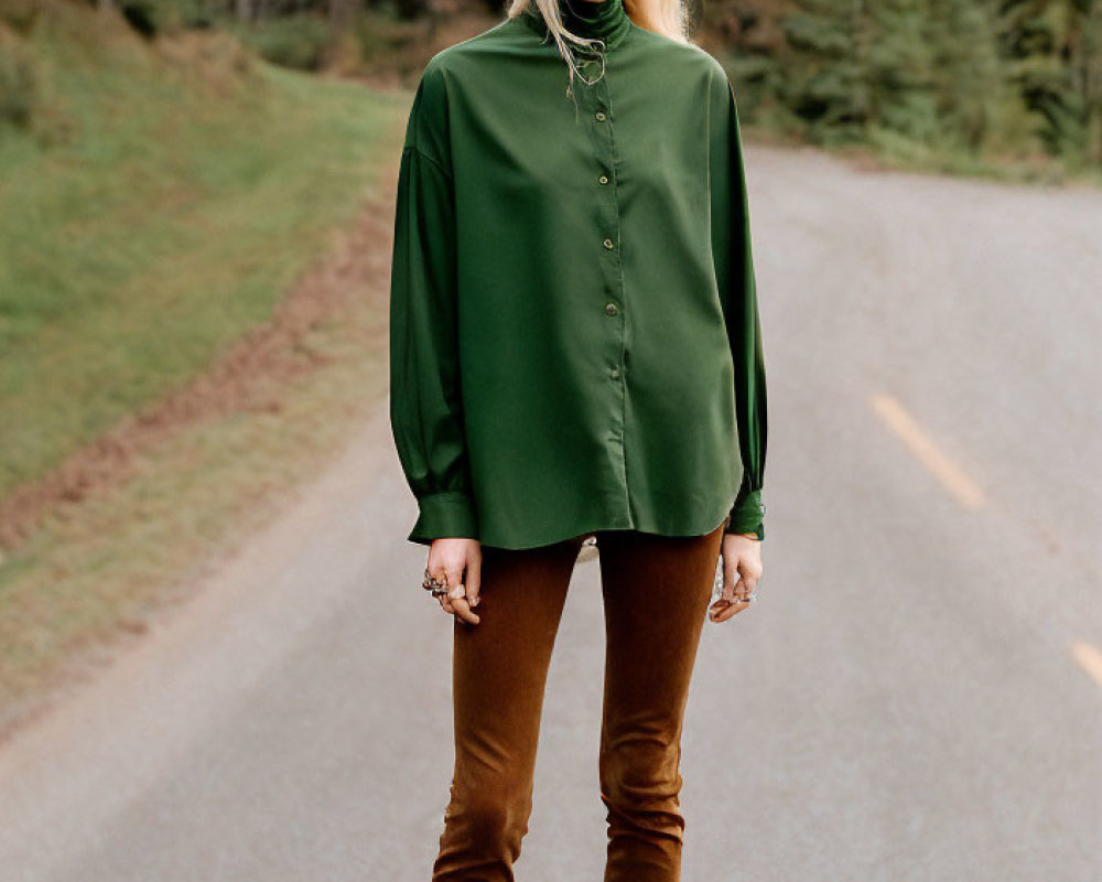 Blonde person in green blouse and brown pants on forest road