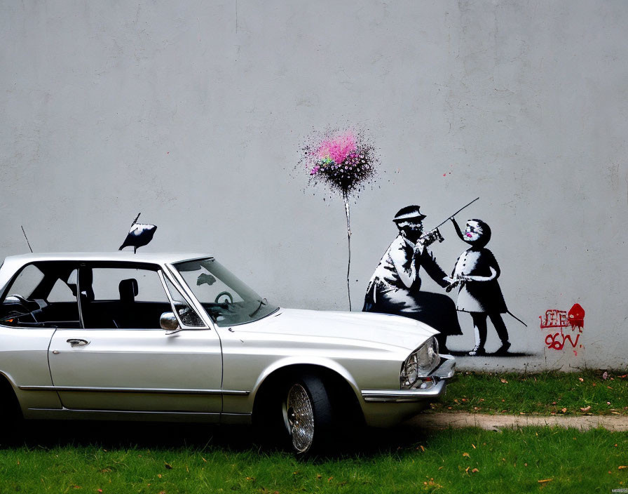 Vintage car parked in front of mural with stenciled man and girl holding heart-shaped balloon.